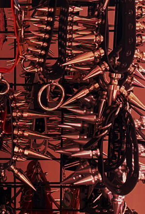 Photography of spiked chokers on display, most likely for sale. There is a red tint over it.